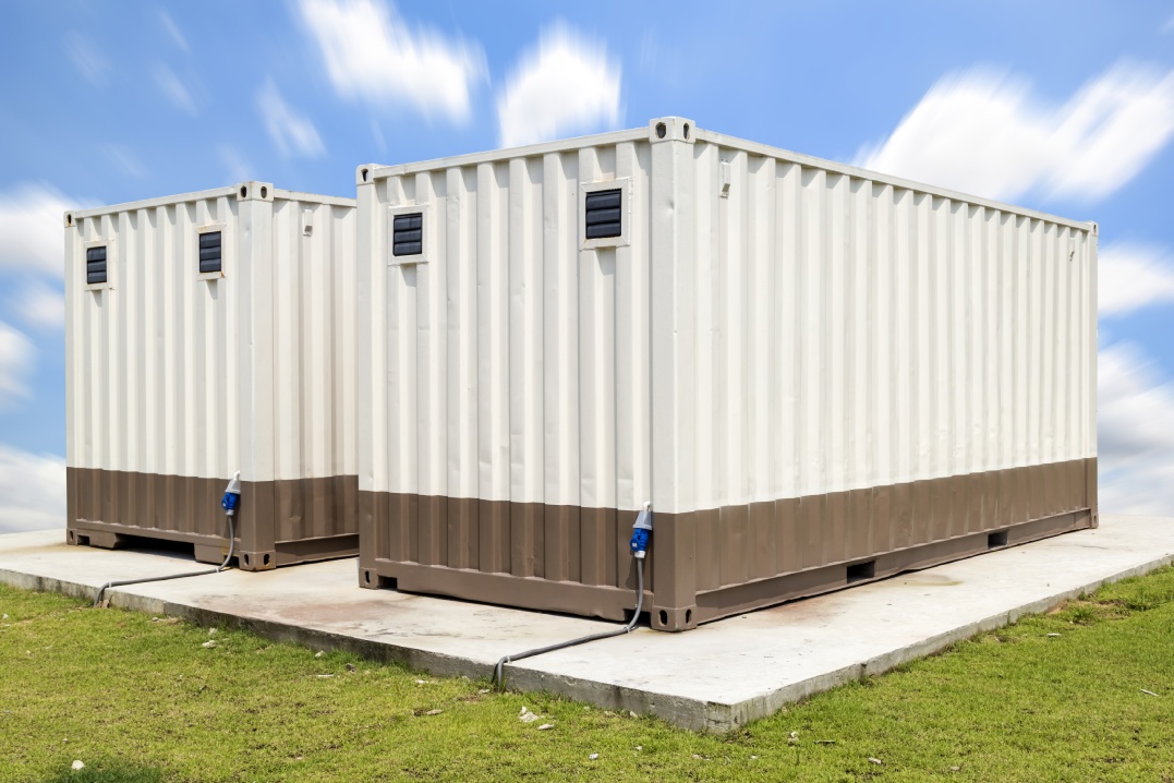 Portable office container or prefabricated modular building. That small mobile workspace, temporary work area, store or storage room for construction site. Consist of metal box and ventilation fan.