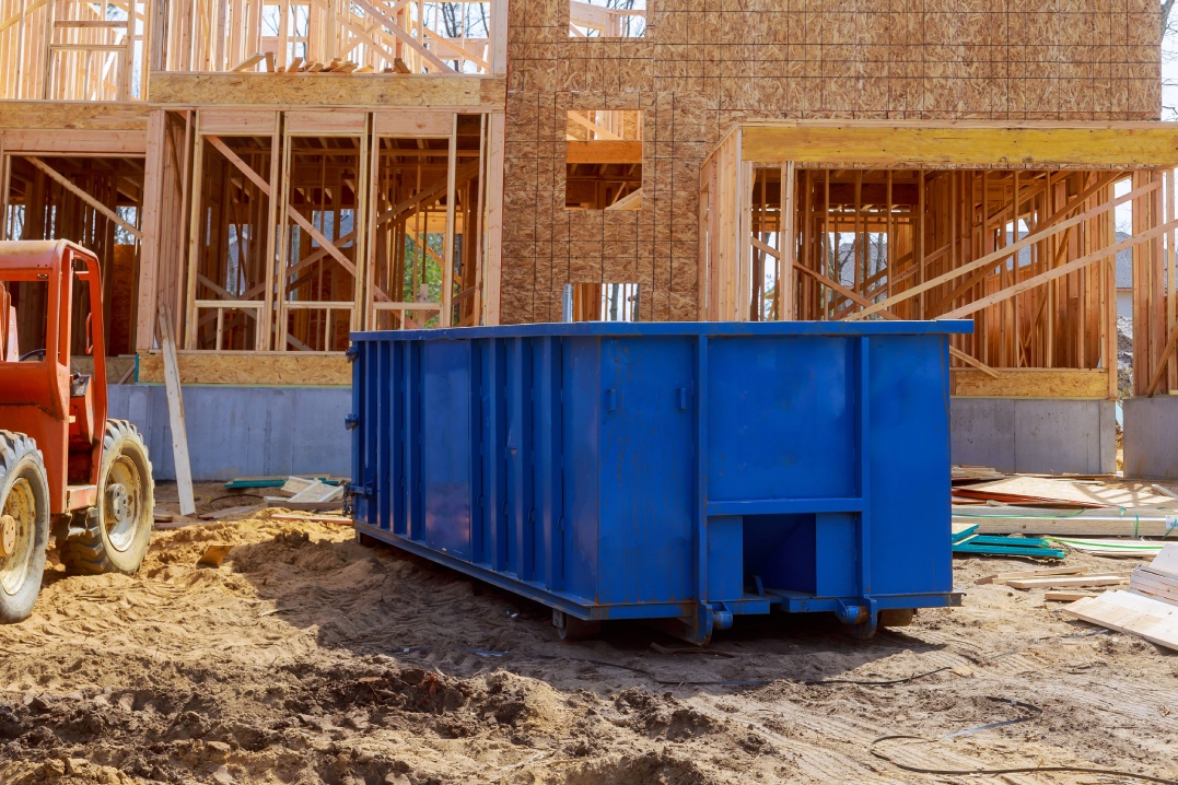 Blur dumpster, recycle waste and garbage bins near new construction site of appartment houses building