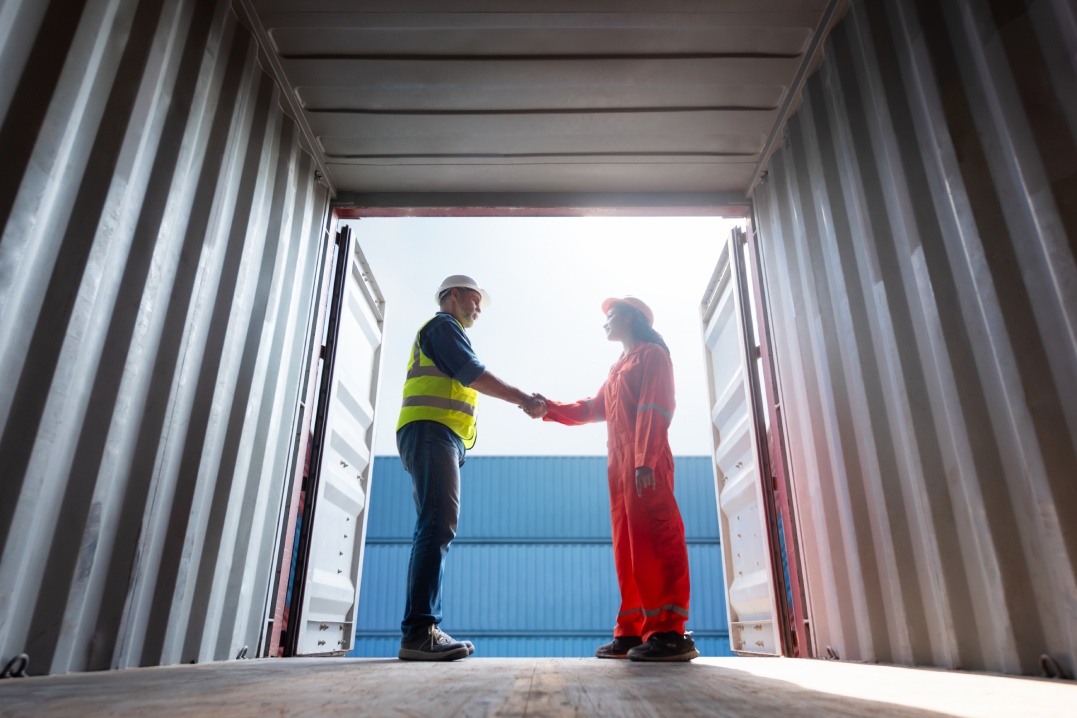 Engineer and worker team shaking hands in construction containers dockyard, Foreman woman work at site check up goods in container, Logistics transportation import export, Success and teamwork concept